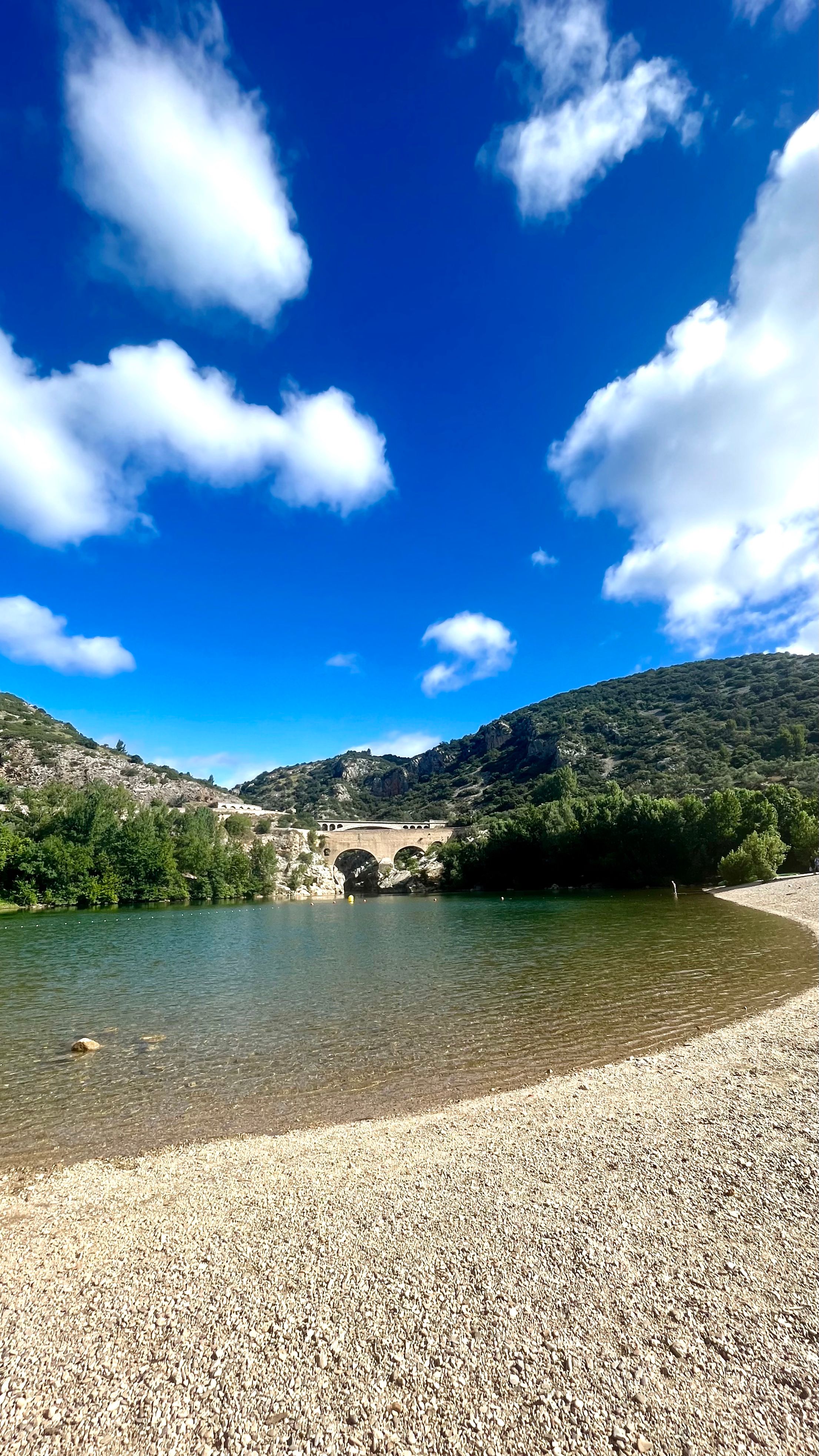 Une plage de galet avec vue sur le pont du Diable dans les gorges de l'Hérault