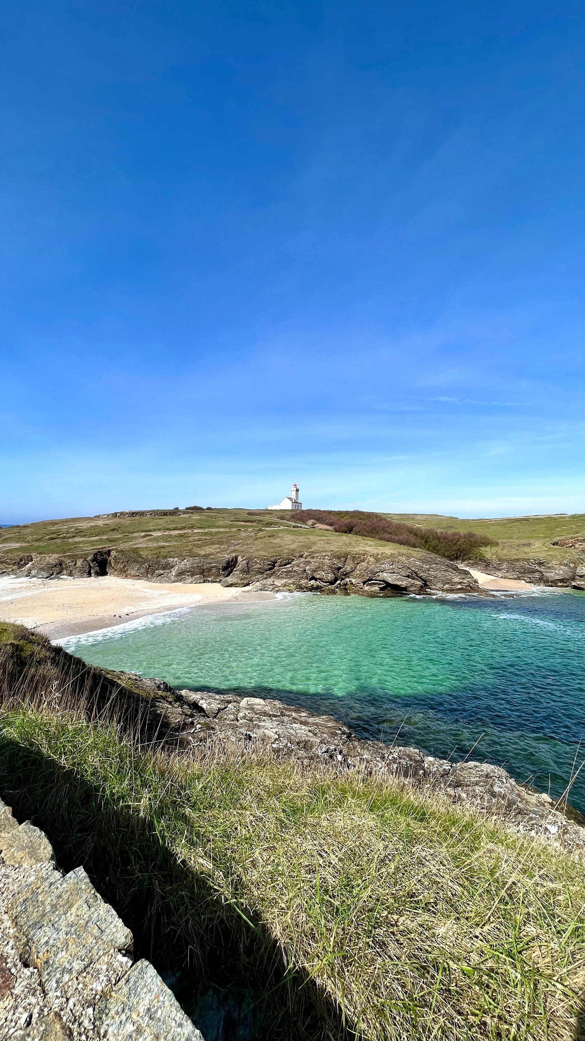 Une plage de sable blanc avec en fond le phare de la pointe des poulains à Belle-Île en Mer